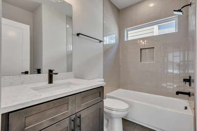 full bathroom featuring tile patterned floors, tiled shower / bath, vanity, and toilet