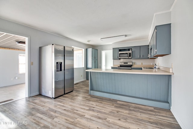 kitchen featuring light hardwood / wood-style floors, kitchen peninsula, stainless steel appliances, ornamental molding, and sink