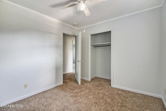 unfurnished bedroom with a closet, baseboards, ceiling fan, crown molding, and carpet floors