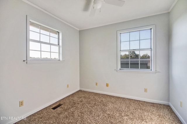 carpeted empty room featuring ornamental molding, visible vents, baseboards, and ceiling fan
