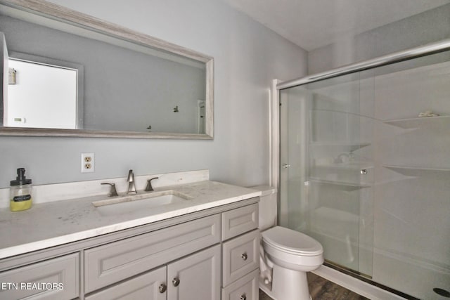 bathroom featuring vanity, a shower with shower door, toilet, and hardwood / wood-style flooring