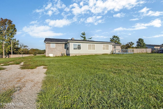 back of house featuring a chimney, fence, and a lawn