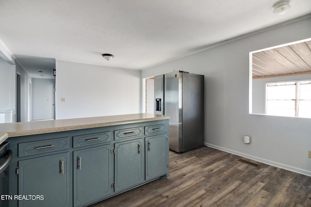 kitchen with baseboards, stainless steel fridge, light countertops, dark wood-type flooring, and visible vents
