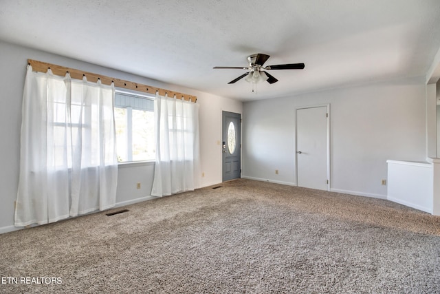 empty room featuring a textured ceiling, carpet, and ceiling fan