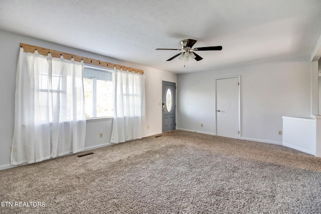 carpeted empty room featuring visible vents, ceiling fan, and baseboards