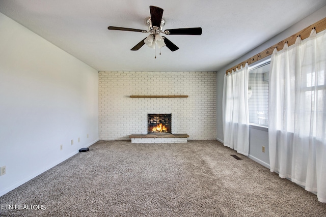 unfurnished living room with a brick fireplace, ceiling fan, and carpet floors