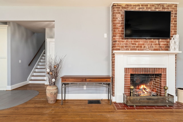 unfurnished living room featuring a brick fireplace and hardwood / wood-style floors