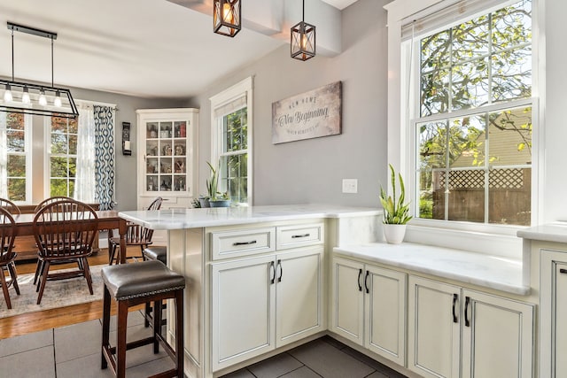 kitchen featuring decorative light fixtures, hardwood / wood-style floors, kitchen peninsula, and a healthy amount of sunlight