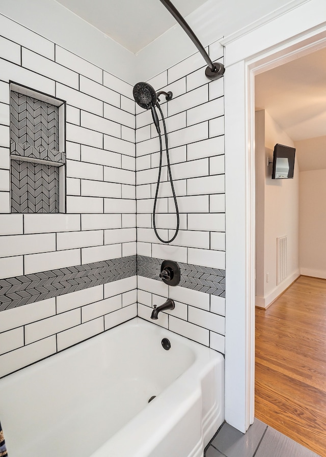 bathroom with tiled shower / bath combo and hardwood / wood-style flooring