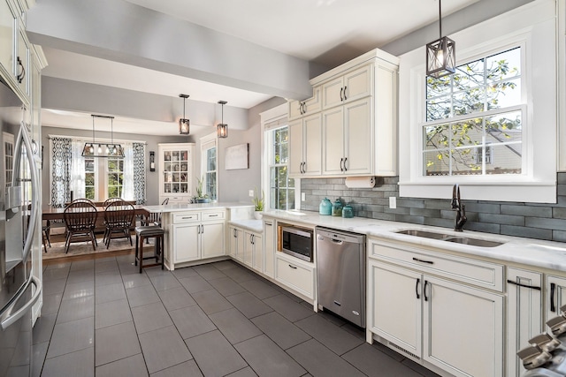 kitchen featuring stainless steel appliances, hanging light fixtures, sink, and a wealth of natural light