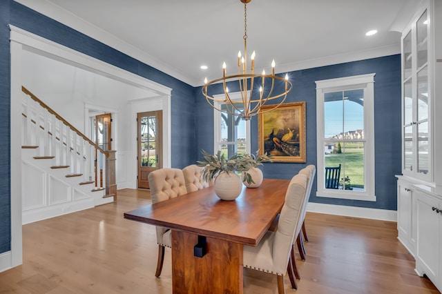 dining space featuring light wood-type flooring, ornamental molding, and a notable chandelier