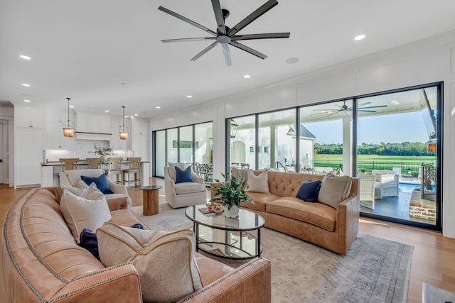 living room featuring light hardwood / wood-style flooring, ceiling fan, and plenty of natural light