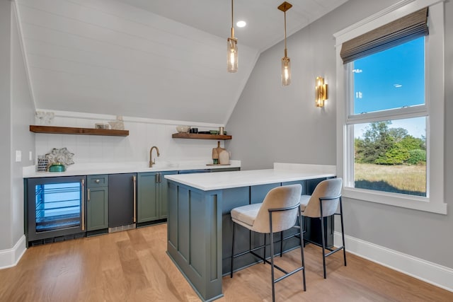 kitchen with hanging light fixtures, stainless steel fridge, kitchen peninsula, a breakfast bar, and light wood-type flooring