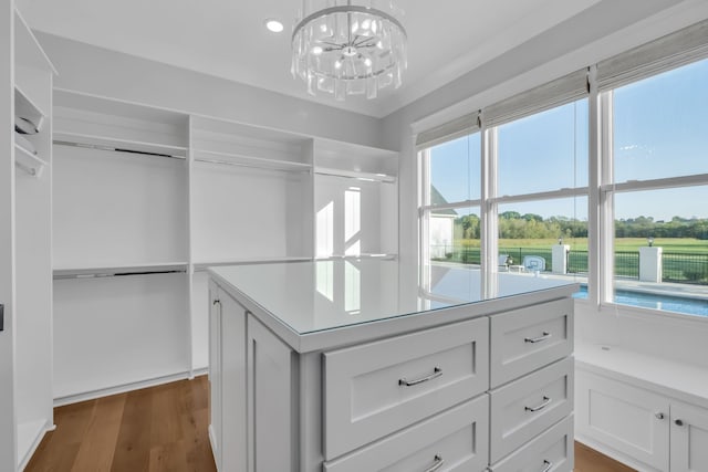 walk in closet with a notable chandelier and dark hardwood / wood-style floors