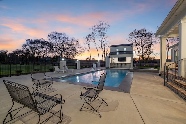 pool at dusk with a patio area