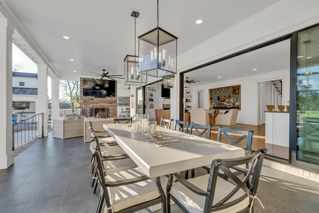 dining room with ceiling fan with notable chandelier and a fireplace