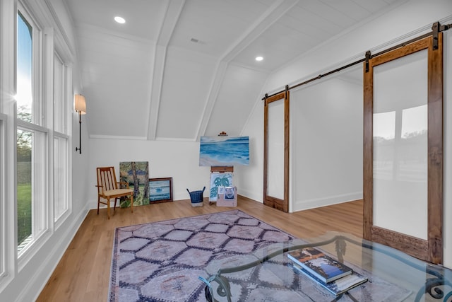 interior space featuring light hardwood / wood-style flooring, lofted ceiling with beams, and a barn door