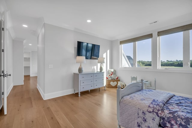 bedroom featuring light wood-type flooring and a spacious closet