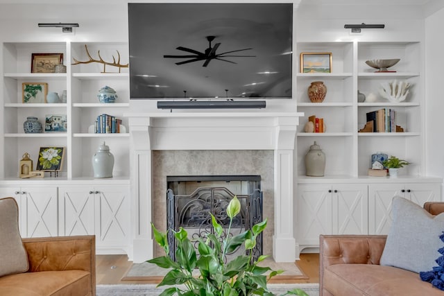 living room with light wood-type flooring, built in shelves, and a tiled fireplace