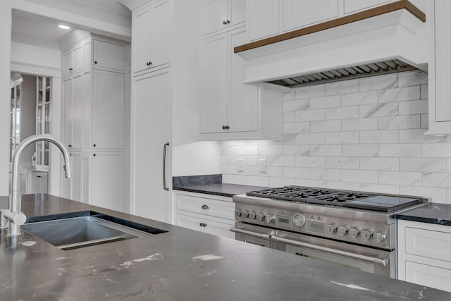 kitchen featuring custom range hood, white cabinetry, tasteful backsplash, sink, and stainless steel range