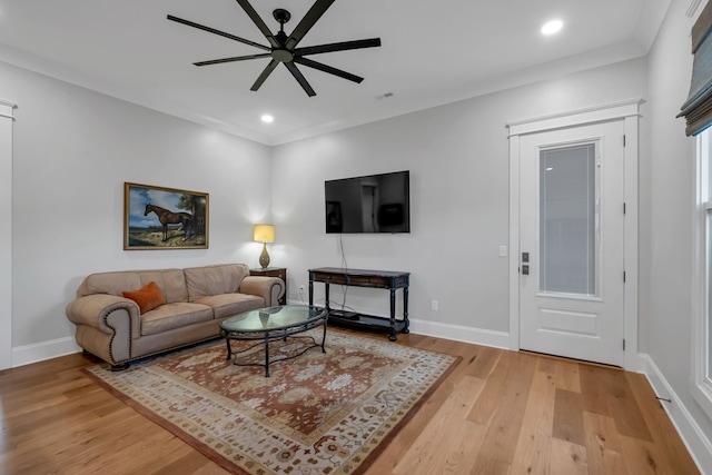 living room with light hardwood / wood-style floors, ceiling fan, and crown molding