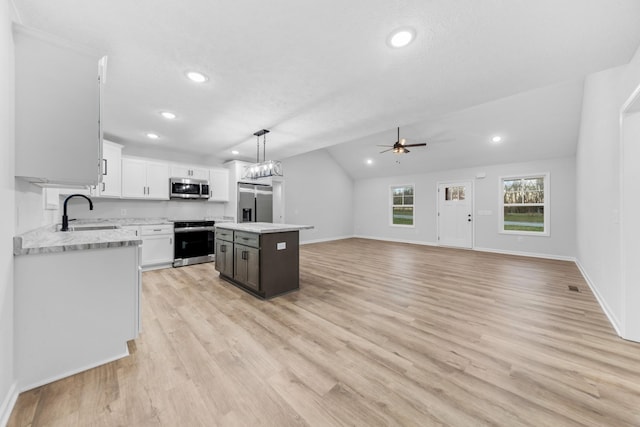 kitchen featuring light wood-style flooring, appliances with stainless steel finishes, white cabinetry, a sink, and a kitchen island