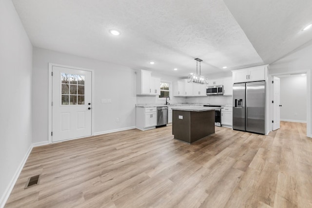 kitchen with light wood finished floors, appliances with stainless steel finishes, a sink, and white cabinetry