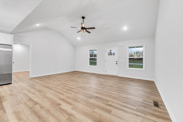 unfurnished living room featuring light wood-style floors, visible vents, vaulted ceiling, and baseboards