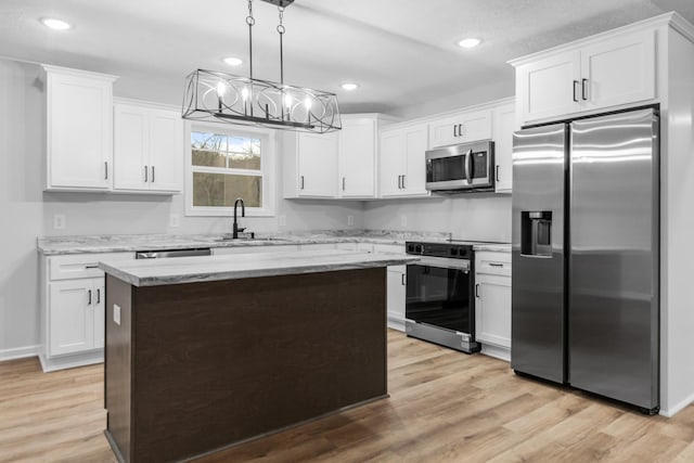 kitchen with light wood finished floors, white cabinets, a kitchen island, appliances with stainless steel finishes, and a sink