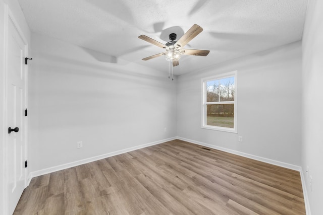 empty room featuring ceiling fan, a textured ceiling, baseboards, and wood finished floors