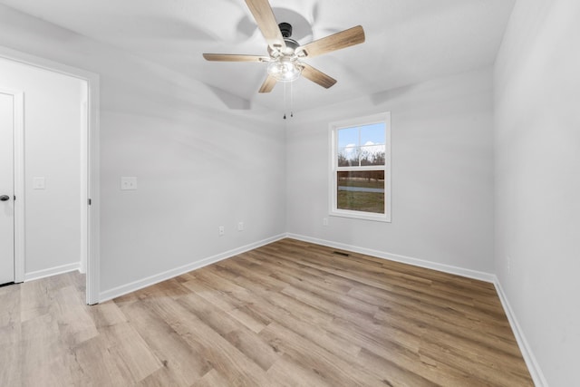 spare room featuring baseboards, a ceiling fan, visible vents, and light wood-style floors