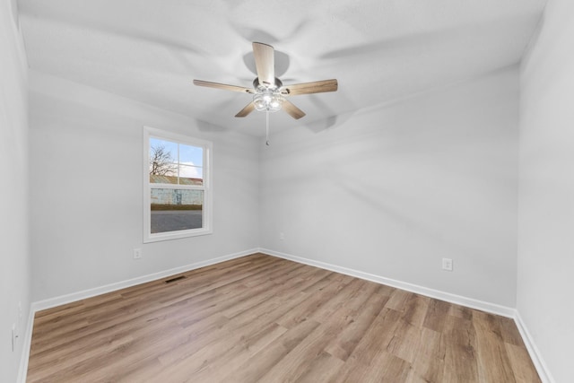 unfurnished room with light wood-style floors, baseboards, visible vents, and a ceiling fan