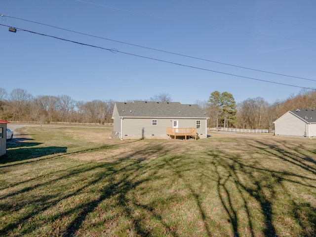 rear view of house featuring a yard, a wooden deck, and fence