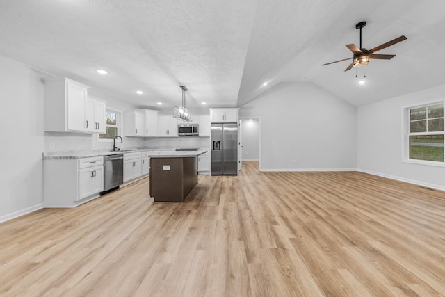 kitchen with a center island, stainless steel appliances, open floor plan, white cabinets, and a sink