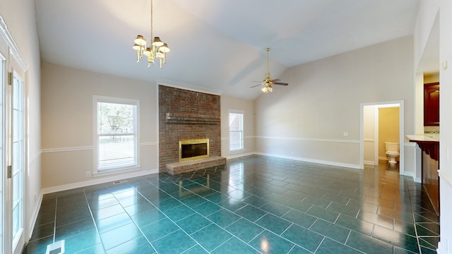 unfurnished living room with a brick fireplace, ceiling fan with notable chandelier, high vaulted ceiling, and dark tile patterned flooring