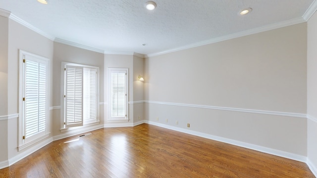 empty room with hardwood / wood-style flooring, ornamental molding, and a textured ceiling