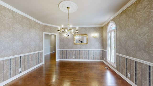 empty room featuring crown molding, dark hardwood / wood-style flooring, and a chandelier