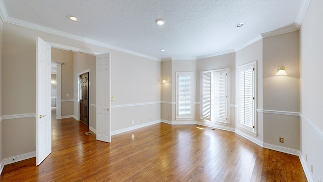 empty room featuring a textured ceiling, crown molding, and hardwood / wood-style floors