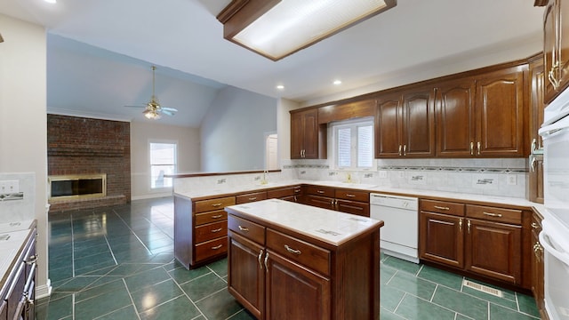 kitchen featuring a center island, lofted ceiling, a brick fireplace, white appliances, and ceiling fan