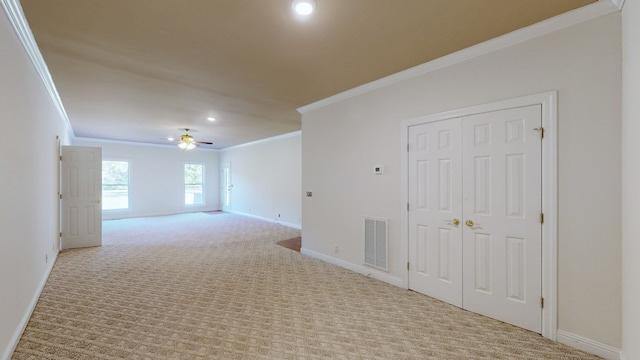 spare room with ceiling fan, light colored carpet, and crown molding