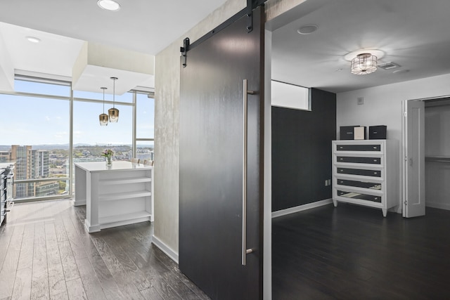 interior space featuring expansive windows, hanging light fixtures, a barn door, and dark hardwood / wood-style floors