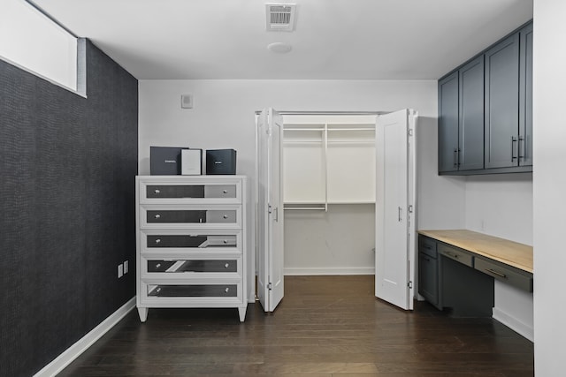 walk in closet with dark wood-type flooring and built in desk