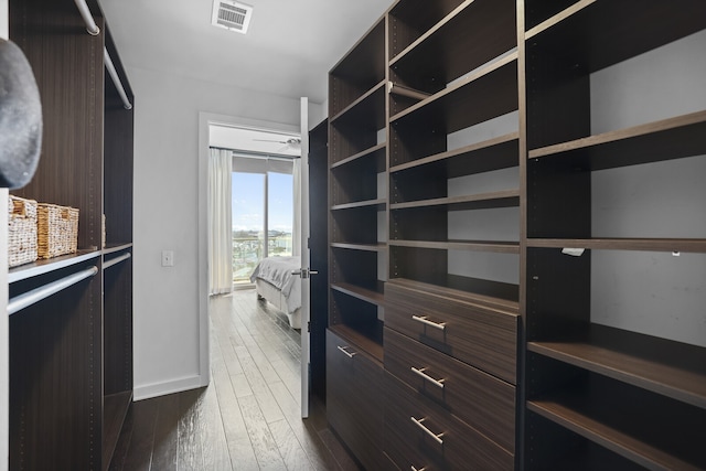 walk in closet featuring dark wood-type flooring and ceiling fan