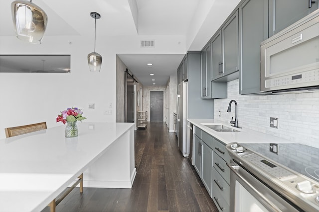 kitchen featuring gray cabinetry, stainless steel appliances, decorative light fixtures, sink, and dark wood-type flooring