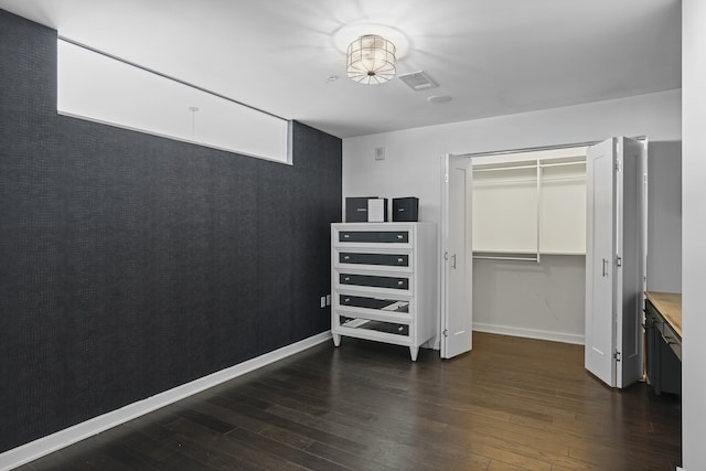 bedroom with dark wood-type flooring and a closet