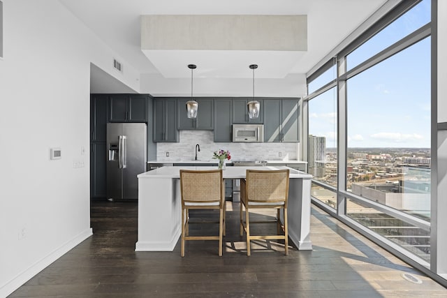 kitchen with tasteful backsplash, appliances with stainless steel finishes, decorative light fixtures, dark hardwood / wood-style flooring, and sink