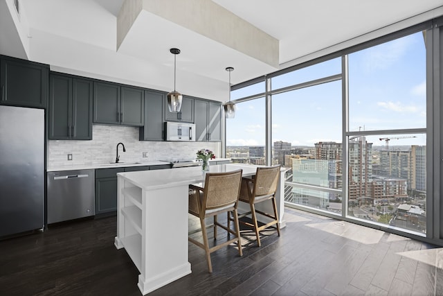 kitchen with stainless steel appliances, dark wood-type flooring, sink, tasteful backsplash, and pendant lighting