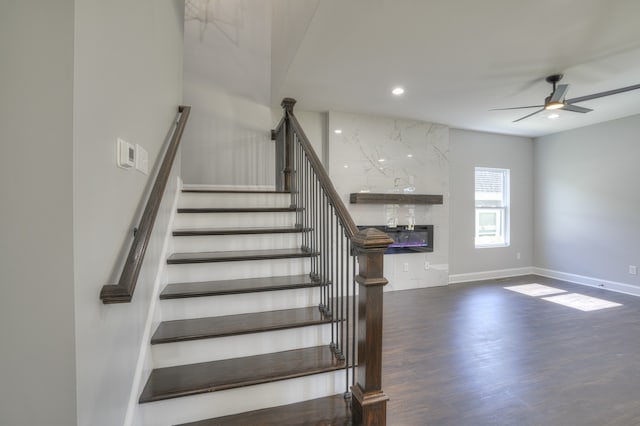 staircase featuring ceiling fan, hardwood / wood-style flooring, and a high end fireplace