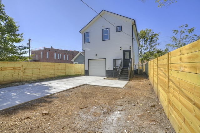 rear view of house with central AC unit and a garage