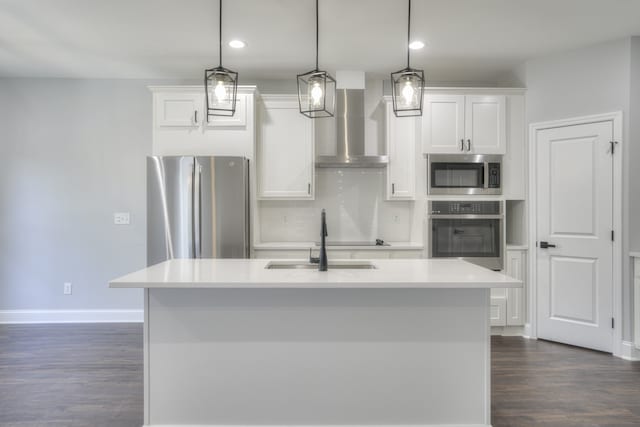 kitchen with appliances with stainless steel finishes, wall chimney exhaust hood, decorative light fixtures, and white cabinets